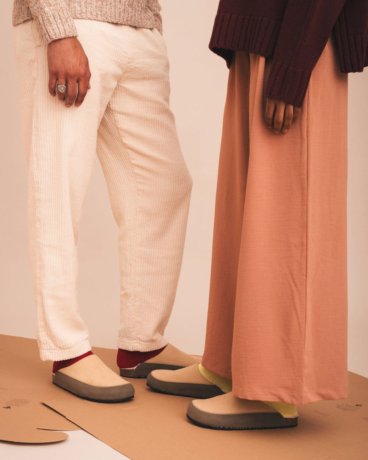 Two people wearing shoes on a plain background