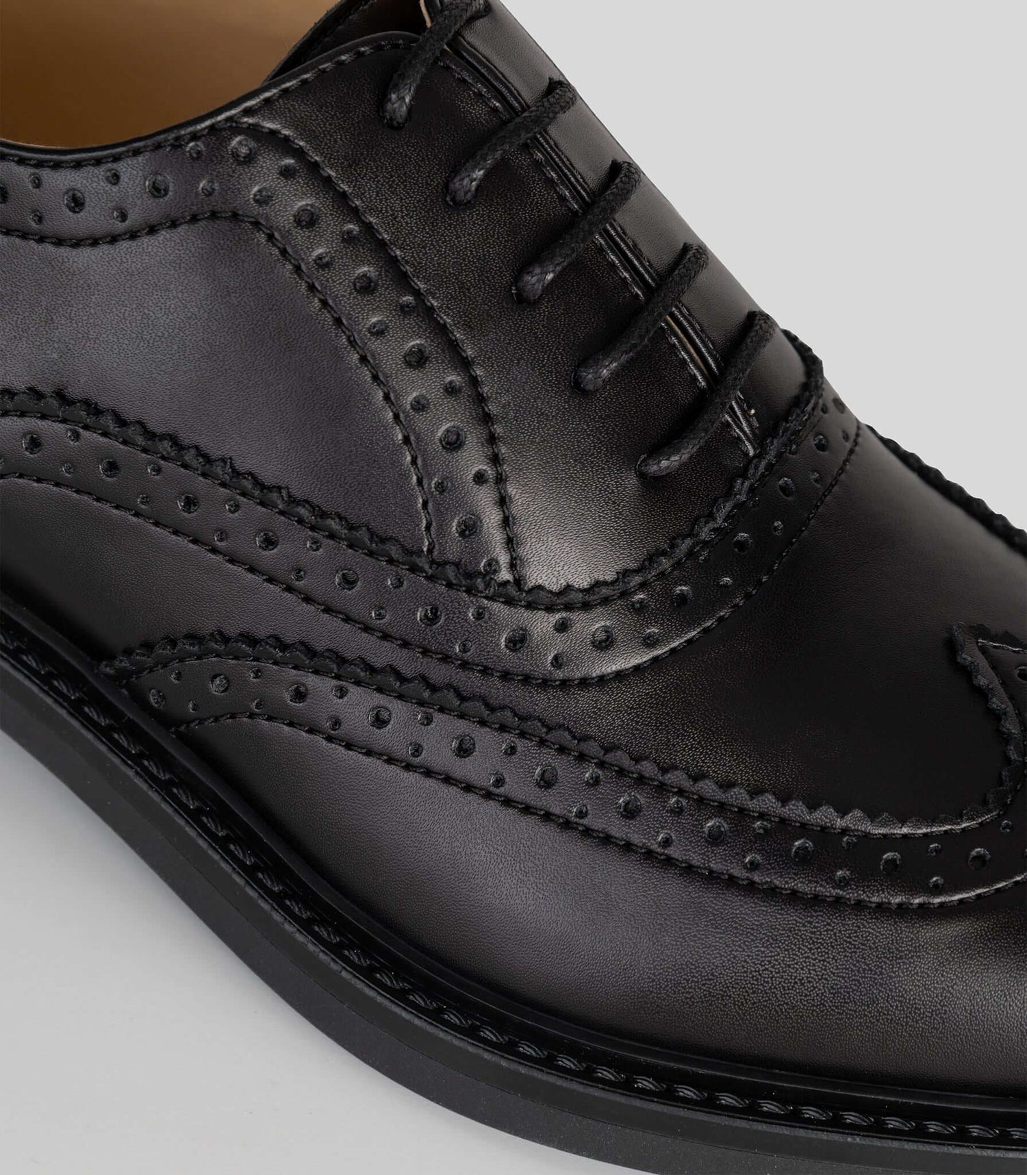 Vegan Oxford Brogue - Woman close-up showing broguing details and sleek black finish.
