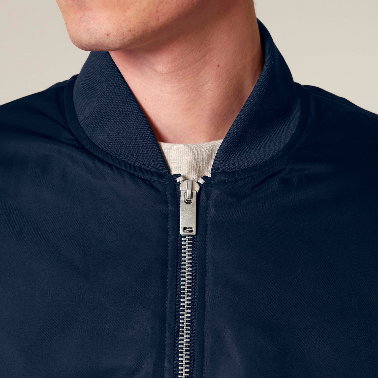 Close-Up of eco-friendly blue unisex bomber jacket with quilted lining and ribbed cuffs, made from GRS-certified recycled polyester