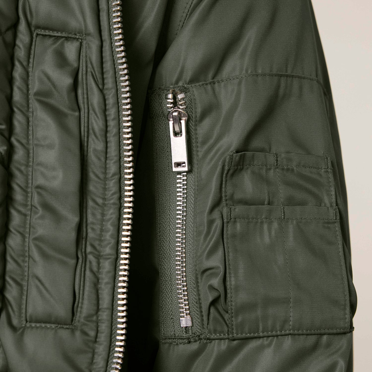 Close Up of green NEW WORLD GUARDIANS GUARDIAN bomber jacket in 100% recycled polyester, sustainable unisex outerwear, 3 colors