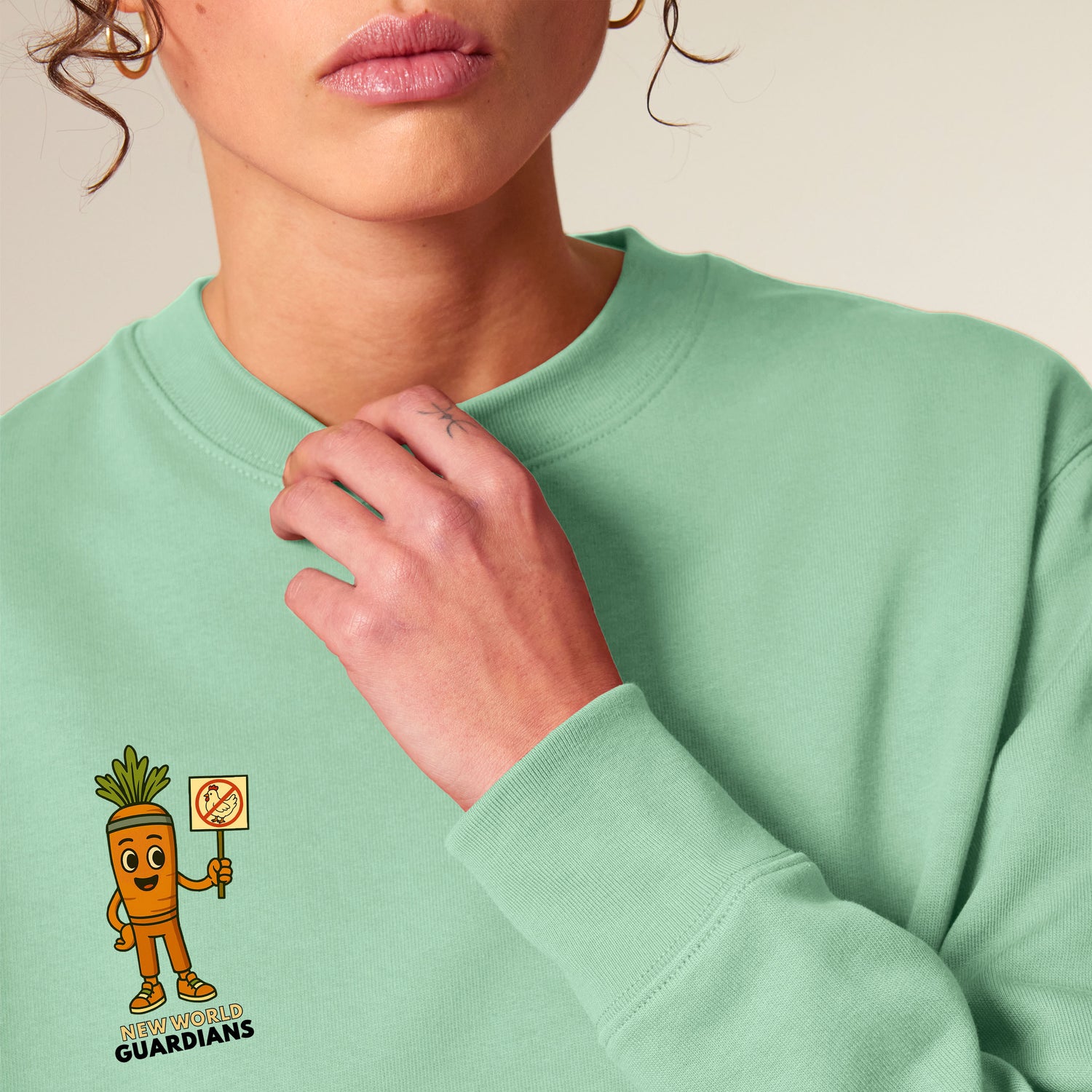 Close-up of female model wearing a Misty Jade NEW WORLD GUARDIANS unisex vegan sweater featuring Crunch the carrot in a comic-style front print. Made from 100% organic cotton. Fresh and conscious vegan fashion meets sustainable streetwear with playful design.