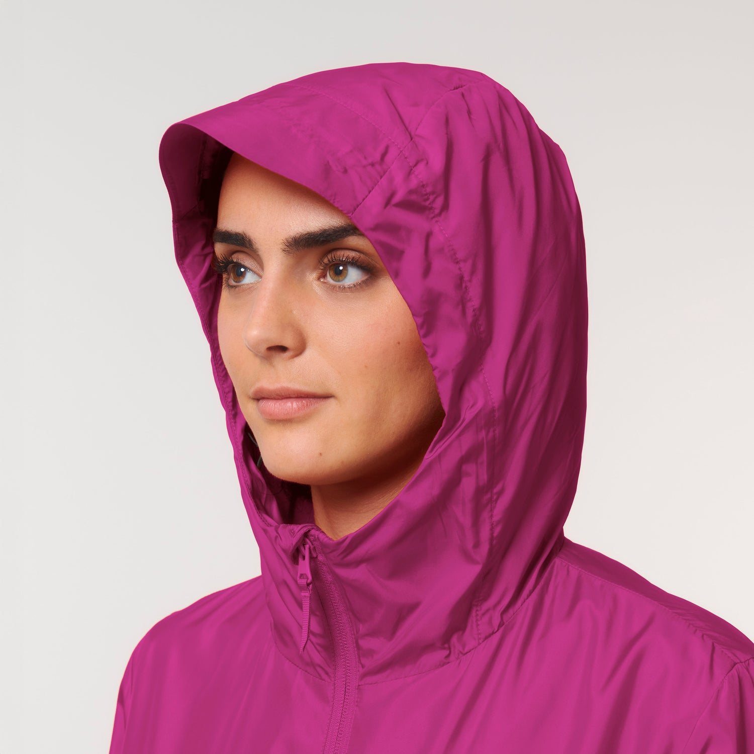 Detailaufnahme der nachhaltigen Multifunktionsjacke in pink mit verlängertem Rückensaum, Kapuze mit versiegelten Nähten und praktischen Taschen