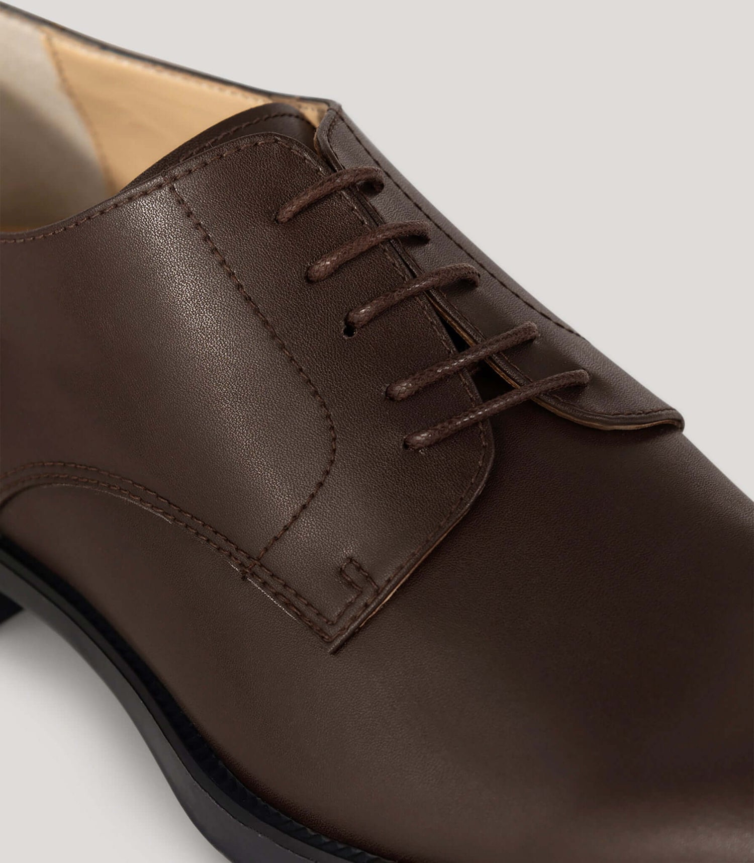 Vegan Derby - Woman close-up showing an elegant brown leather shoe with open lacing system for versatile occasions.