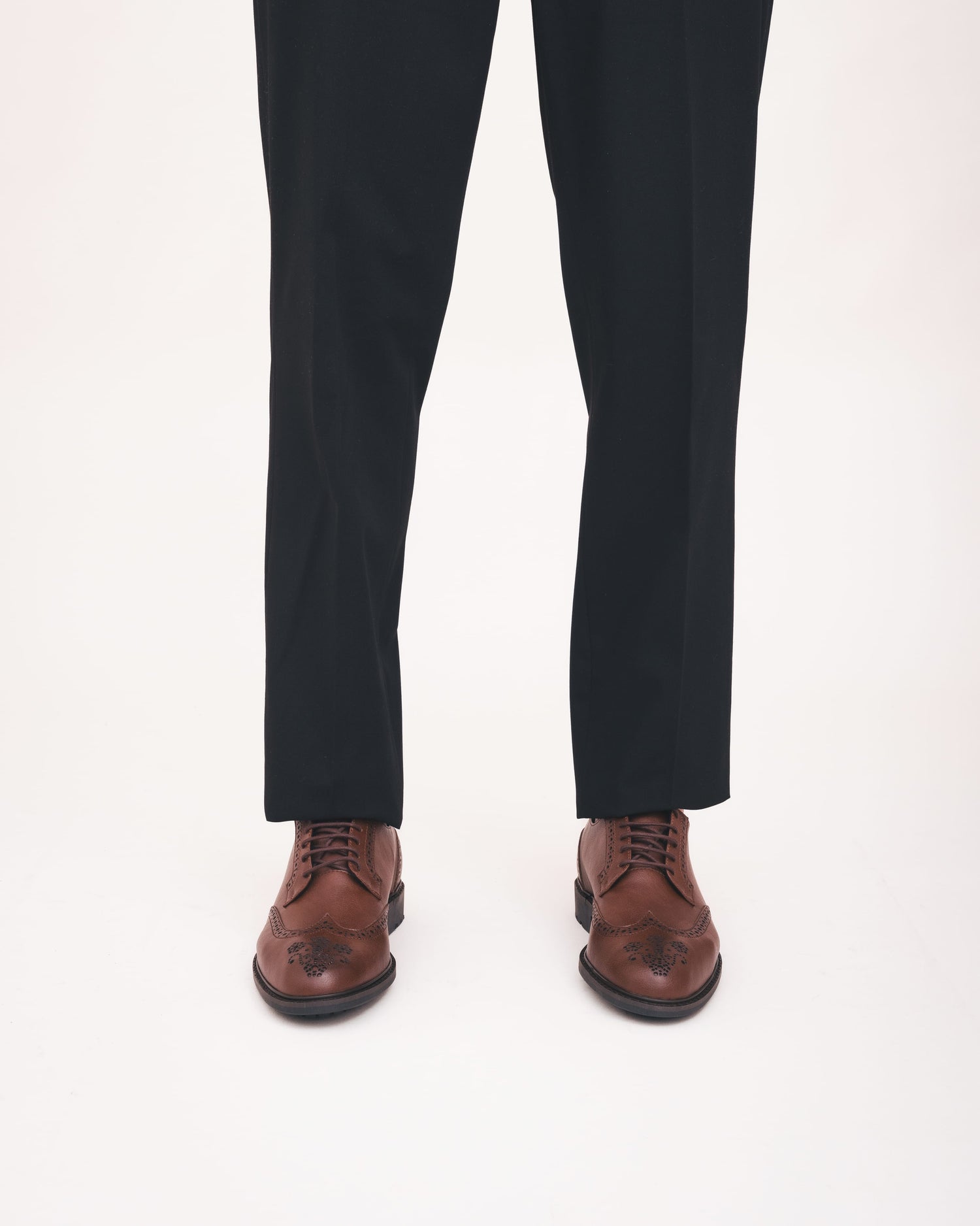 Black pants with brown dress shoes on a white background