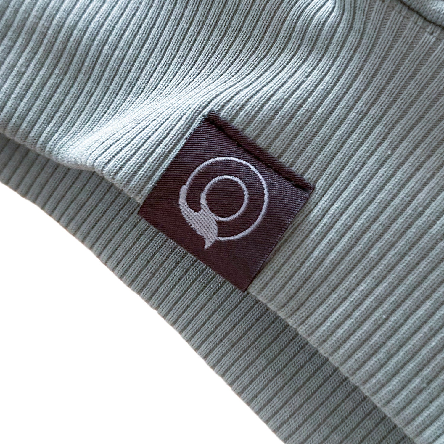 NEW WORLD GUARDIANS Hoodie Close-Up with a grey label featuring a white logo on a white background