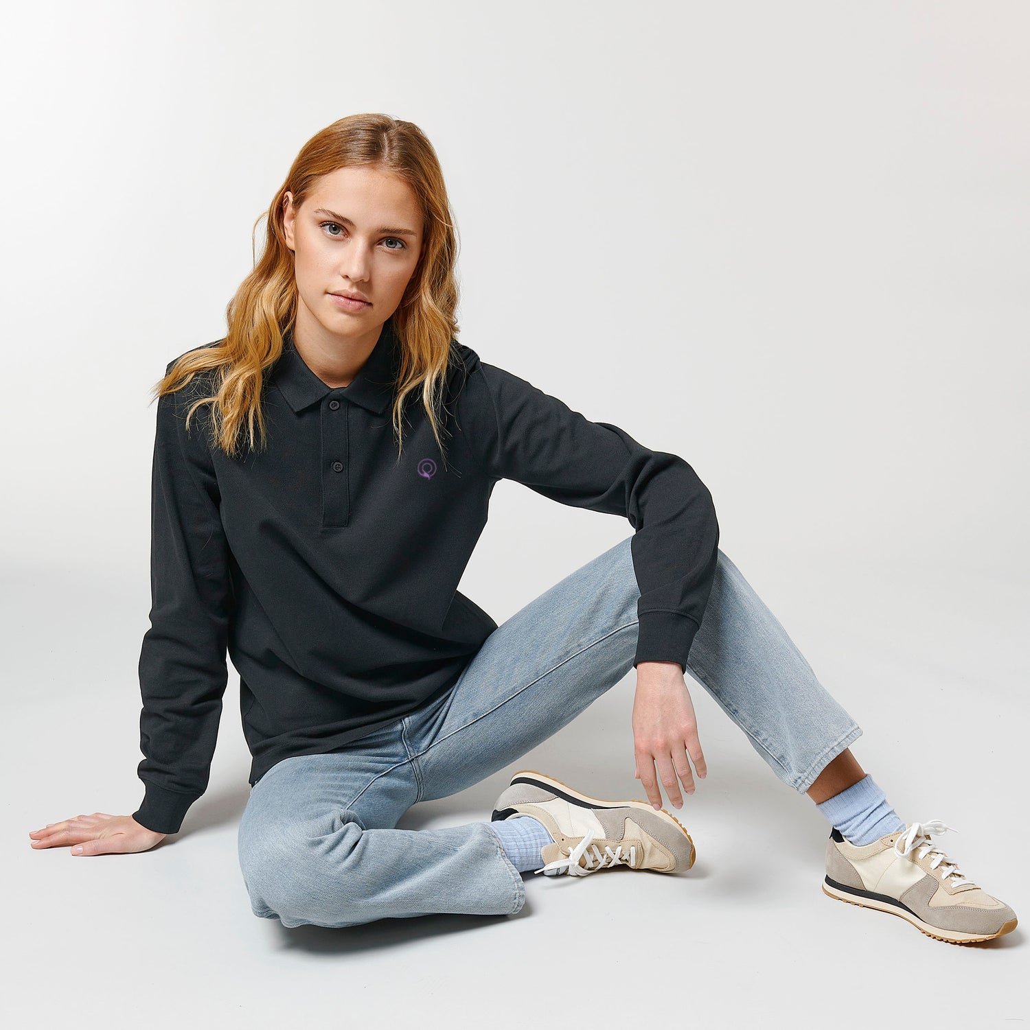Female model wearing a black long sleeve unisex polo shirt – sustainable and ethically made fashion by New World Guardians.