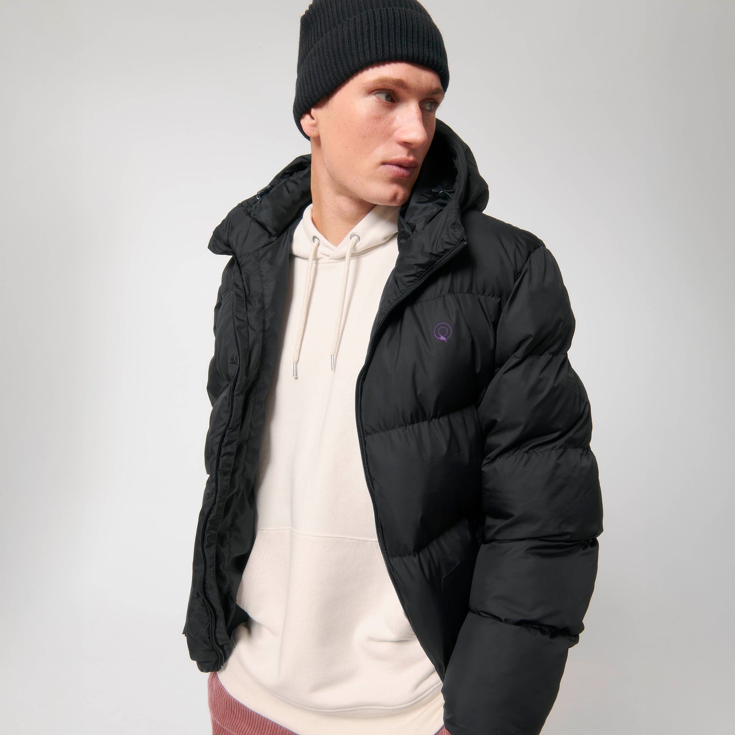 Model trägt eine schwarze warme, leichte Unisex Guardian Pufferjacke aus recyceltem Polyester, bewusst nachhaltig und funktional
