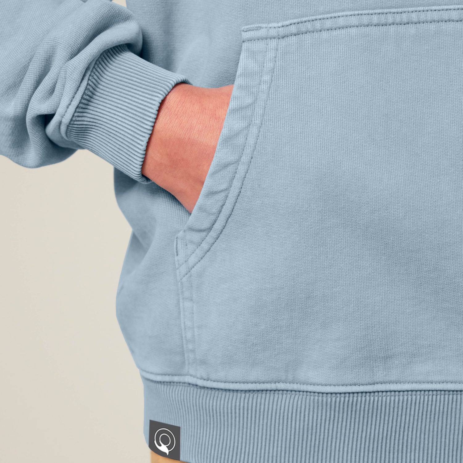 Close-up of blue NEW WORLD GUARDIANS unisex vegan hoodie showing kangaroo pocket detail with hand tucked in. Made from 100% organic cotton. High-quality sustainable streetwear and soft vegan fashion essentials.