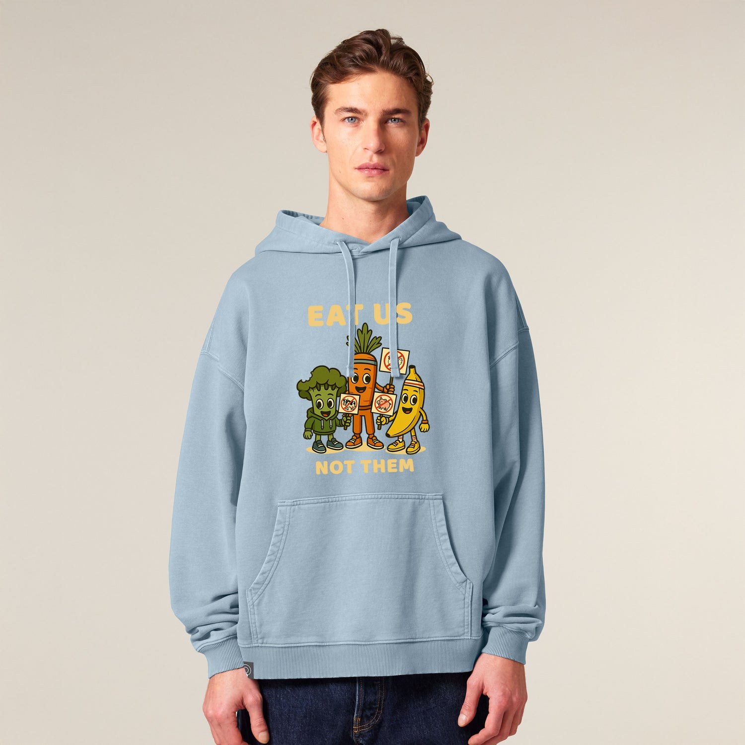Male model wearing a blue NEW WORLD GUARDIANS unisex vegan hoodie featuring the full Roots for Our Future veggie squad in a large comic-style front print with the slogan “Eat Us Not Them”. Made from 100% organic cotton. Bold vegan fashion and sustainable streetwear with impact.
