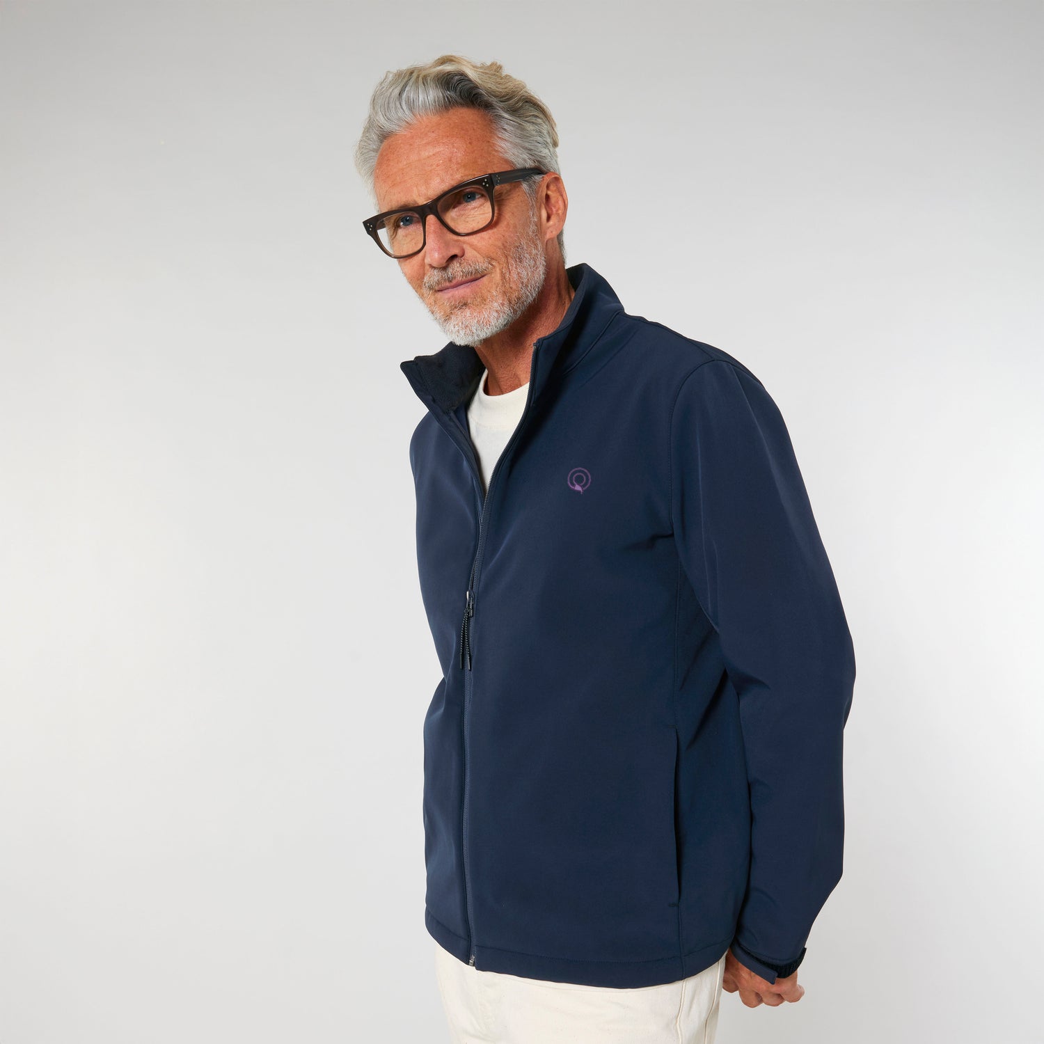Man wears a navy blue Explorer softshell jacket with high collar, tailored fit, and stretch side panels, men’s eco outerwear, 4 colors