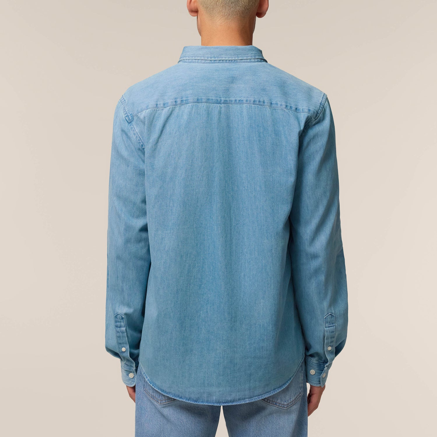 Back view of a male model wearing a denim shirt in light wash – sustainable and ethically made fashion by New World Guardians.