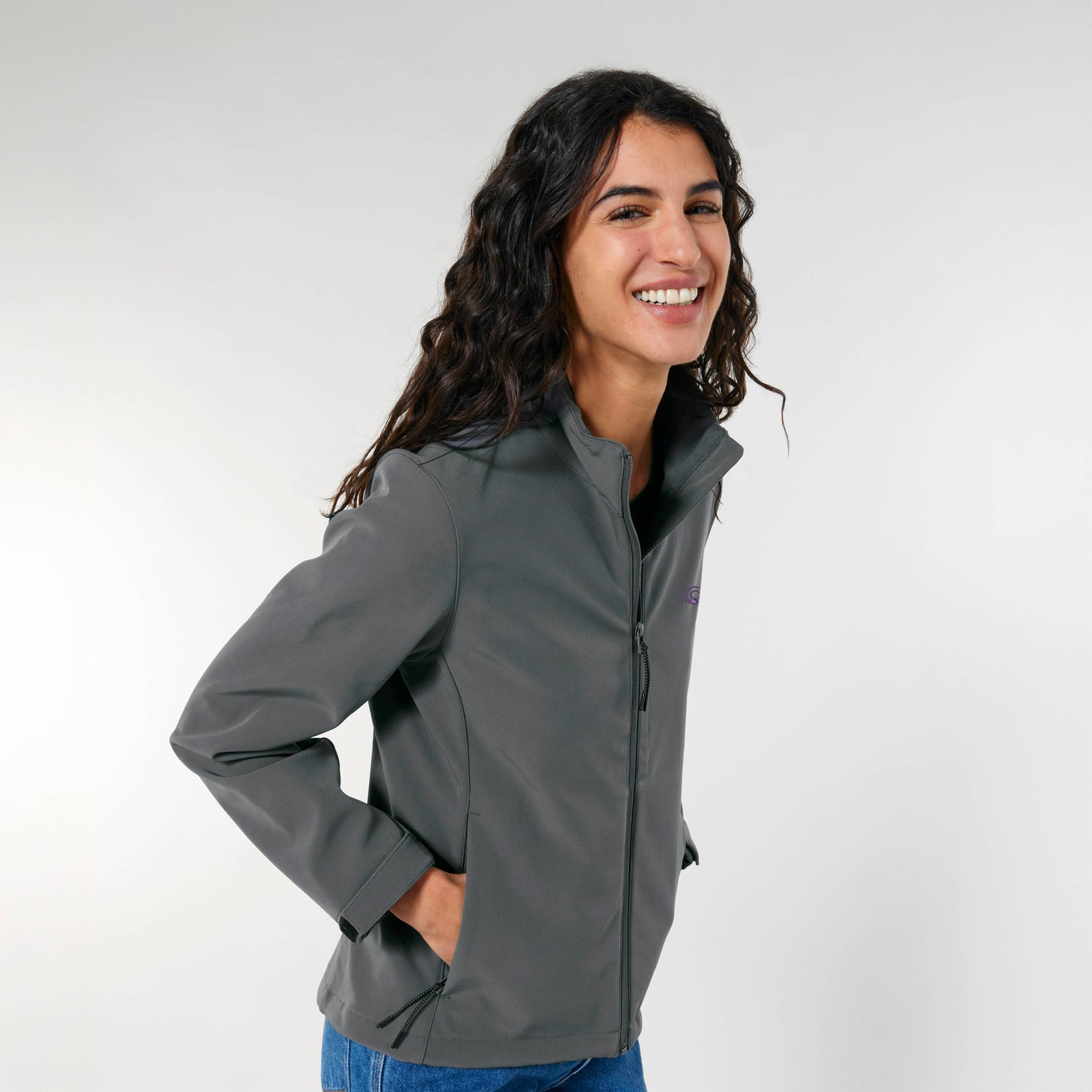 Eine Frau trägt eine graue nachhaltige NEW WORLD GUARDIANS Damen-Outdoorjacke aus recyceltem Polyester mit figurbetontem Schnitt und praktischen Details