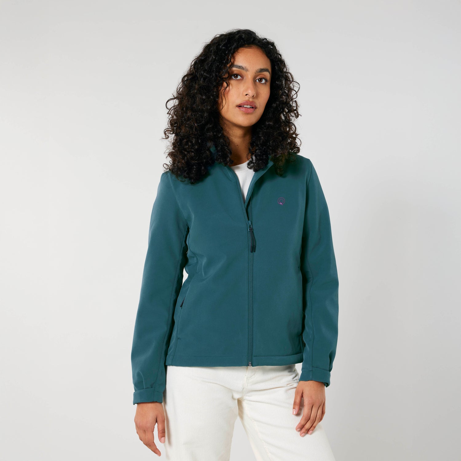 A woman wearing a green NEW WORLD GUARDIANS Explorer jacket, eco-friendly women’s softshell with feminine silhouette, 4 color variations