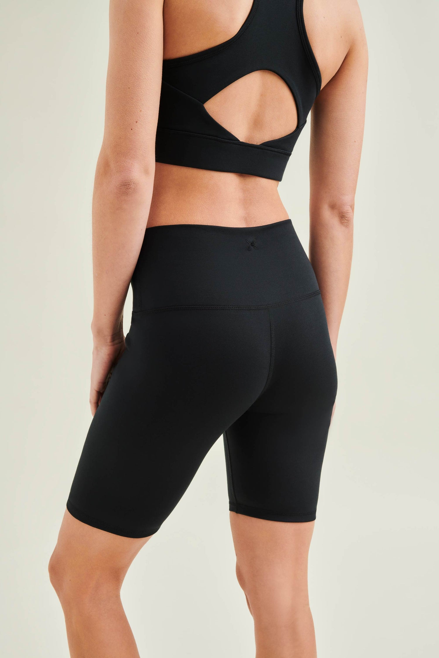 Model wearing Wellicious sustainable yoga wear with black Control Bra and high waist shorts made from organic cotton and biodegradable elastane