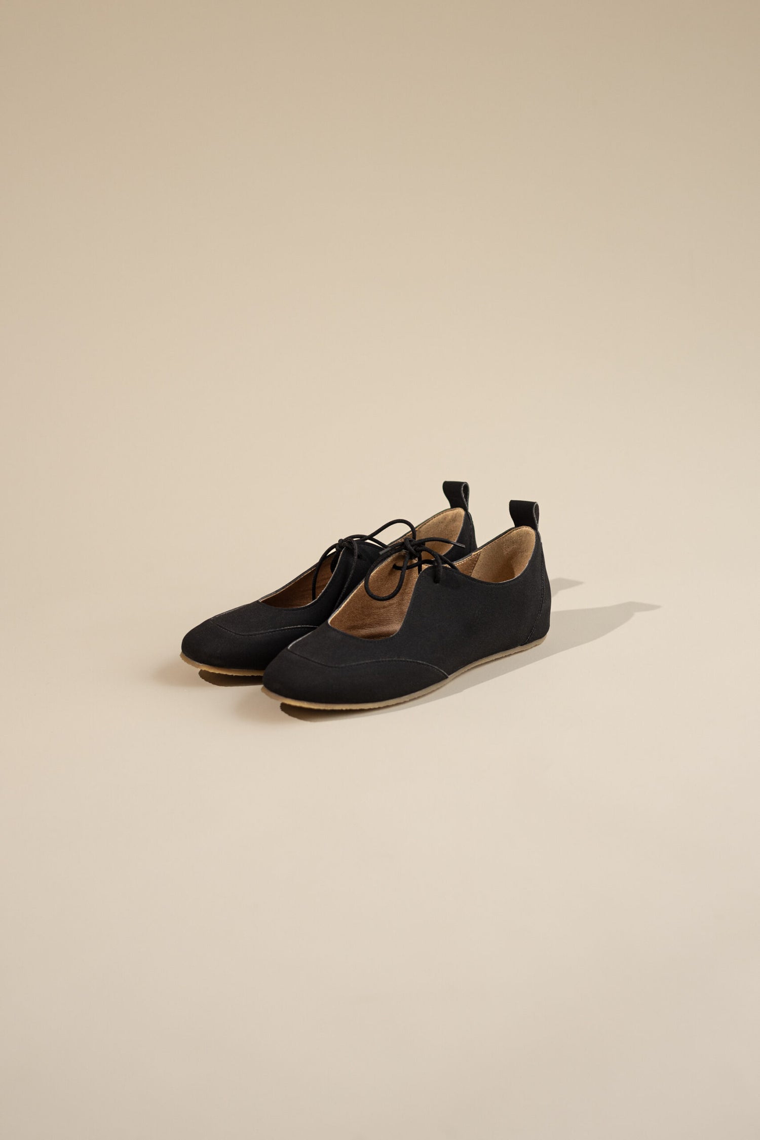 Pair of black vegan shoes on a beige background