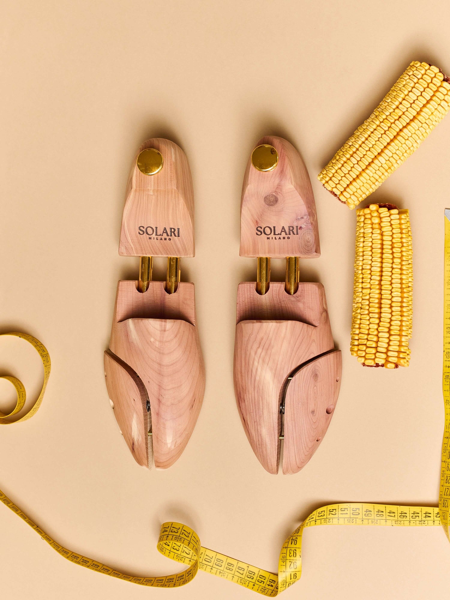 Premium cedar wood Shoe Trees displayed on a beige background with measuring tape and yellow corn decor.