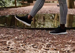 A young woman wearing black and white Explorer V2 hemp shoes for women, takes a stroll through a park.