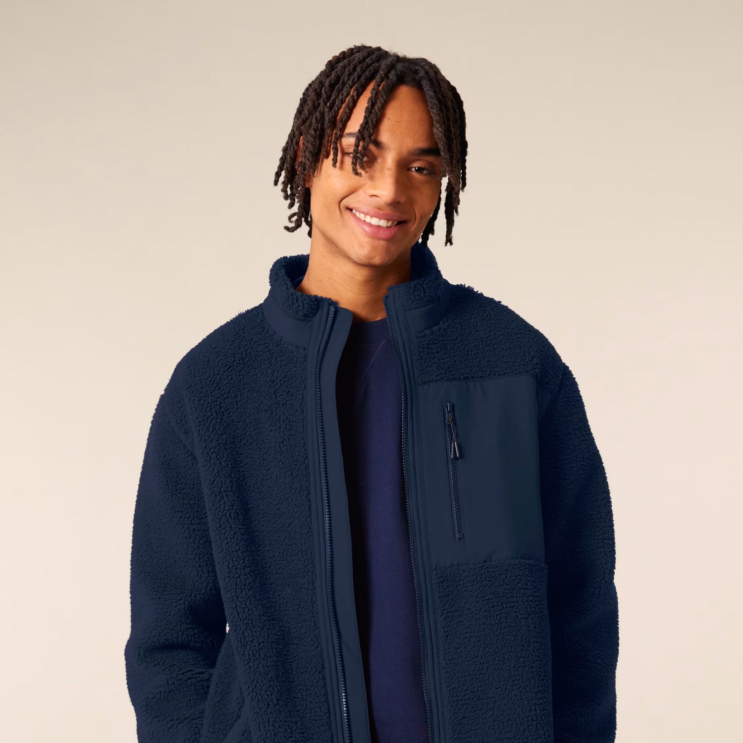 Man wearing a sustainable navy blue fleece jacket on a beige background