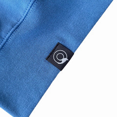 Close-up of a blue NEW WORLD GUARDIANS Sweater with a brand logo tag on a white background