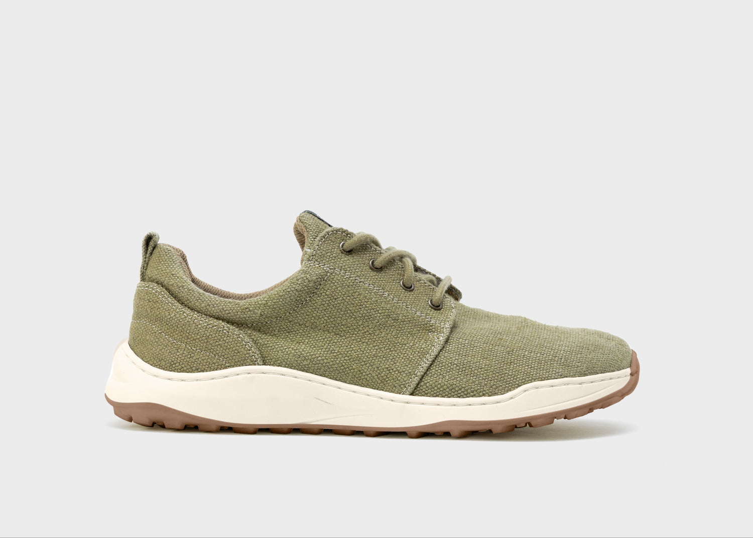 Green sneaker with white sole on a light gray background