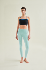 Woman wearing a black eco-conscious sports bra and light blue sustainable high-waste leggings - sustainable, Cradle to Cradle Certified® activewear for mindful living