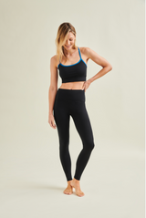 Woman wearing a black sports bra and high-waisted circular leggings by Wellicious, showcasing toxin-free and microplastic-free fabric