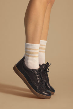 Person wearing black vegan sneakers and white socks with yellow stripes