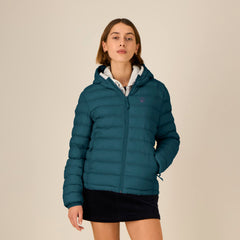 Woman wearing a teal puffer jacket on a beige background
