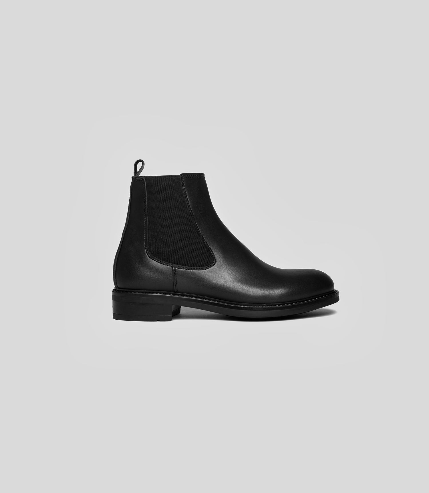 Vegan Chelsea boots - Woman in black leather with elastic side panels, showcasing elegance and sustainability.