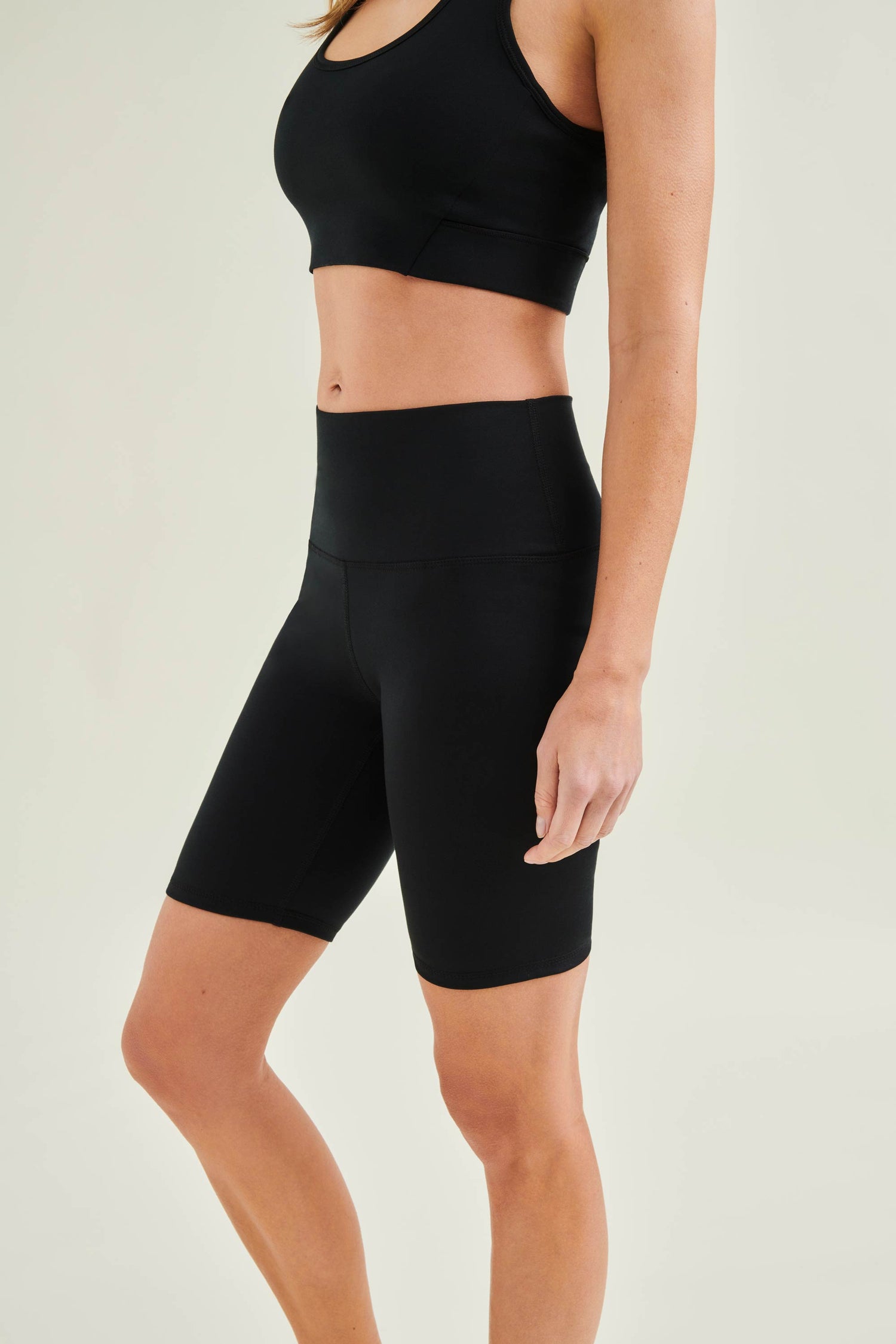 Model wearing Wellicious sustainable yoga outfit with black Control Bra and high waist shorts