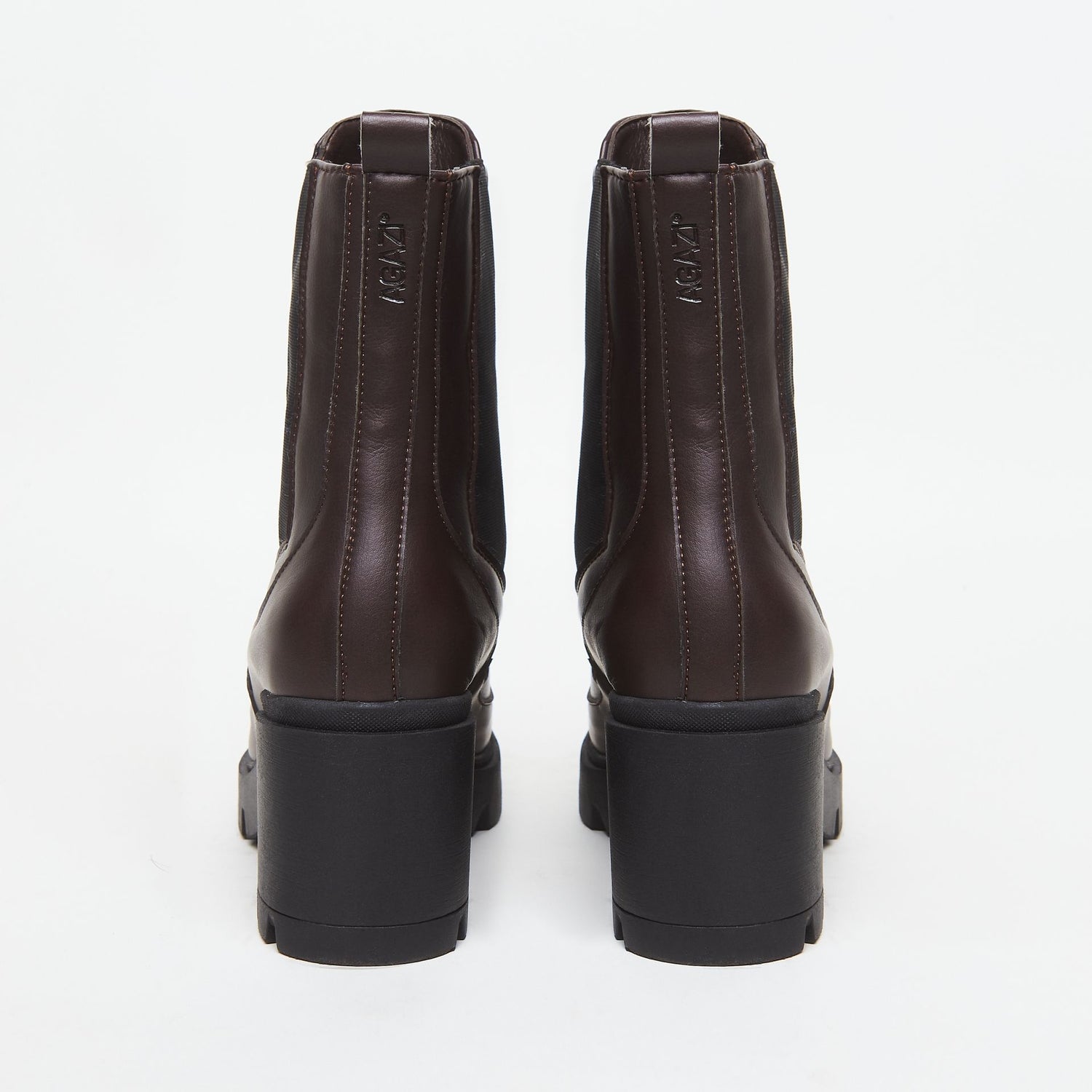 Pair of brown vegan leather boots with black soles on a white background