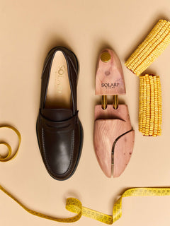 Premium cedar wood Shoe Trees placed beside a sleek black shoe and measuring tape on a beige background.