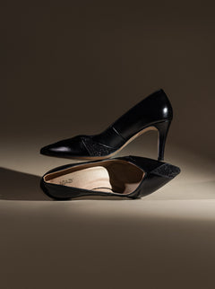 Black vegan high-heeled shoes on a brown background