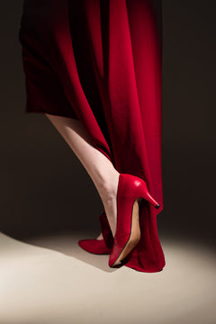 Red vegan high-heeled shoes worn by a woman.